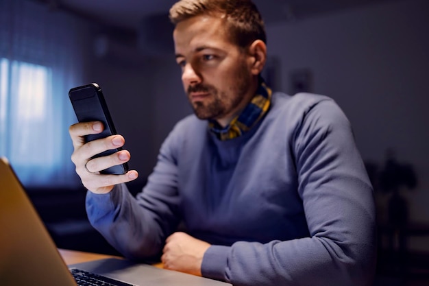 Close-up de um homem usando seu celular em casa