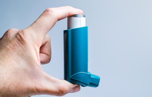 Foto close-up de um inalador de astma nas mãos sobre um fundo branco