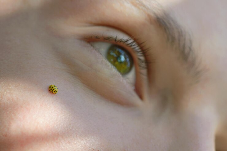 Foto close-up de um inseto amarelo no rosto de um menino adolescente