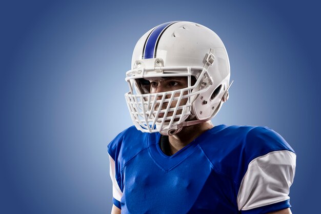 Close-up de um jogador de futebol com um uniforme azul em uma parede azul