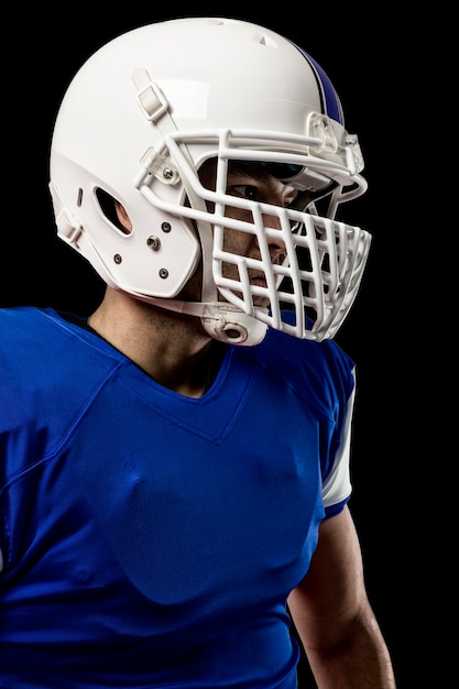 Close-up de um jogador de futebol com um uniforme azul em uma parede preta