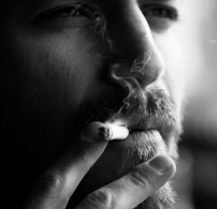 Foto close-up de um jovem a fumar um cigarro