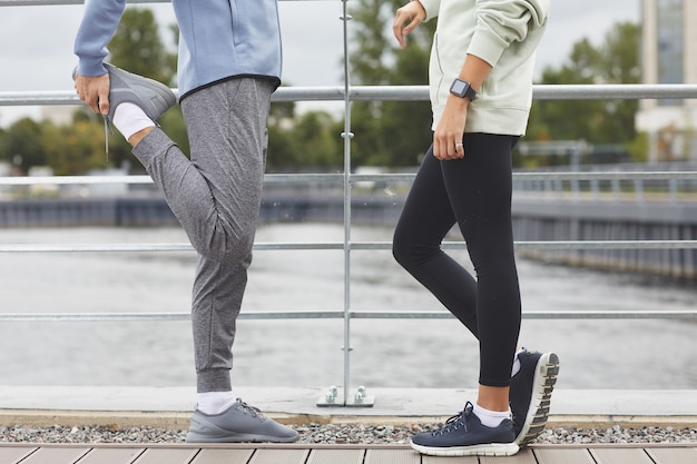 Close-up de um jovem casal em roupas esportivas, em pé na ponte, conversando durante o treinamento esportivo ao ar livre