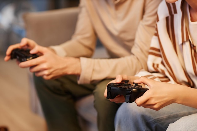 Close-up de um jovem casal jogando videogames em casa e segurando controladores de espaço de cópia