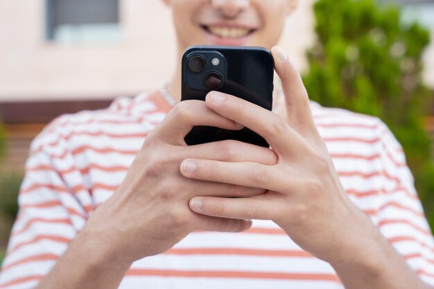 close-up de um jovem sorridente usando um aplicativo de smartphone ao ar livre