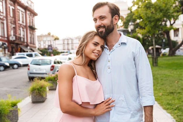 Close-up de um lindo casal feliz se abraçando em pé na rua da cidade, se abraçando