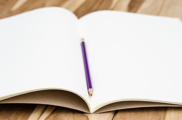 Foto close-up de um livro em branco com um lápis na mesa