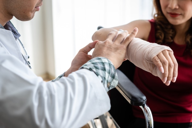 Close-up de um médico com uma tala de bandagens de enfermeira de embrulho para o braço de uma paciente do sexo feminino usar uma tala de braço com manômetro analógico para uma melhor cicatrização