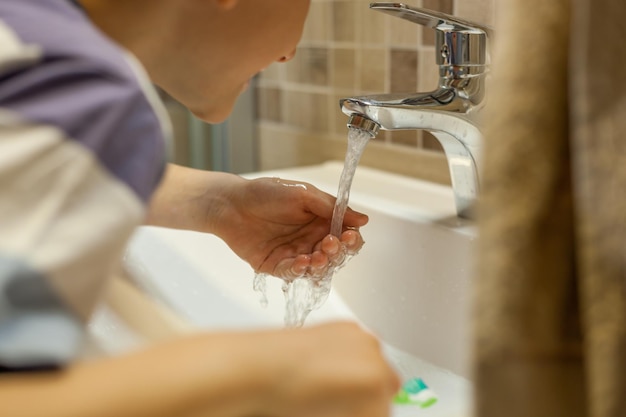Foto close-up de um menino a escovar os dentes na casa de banho