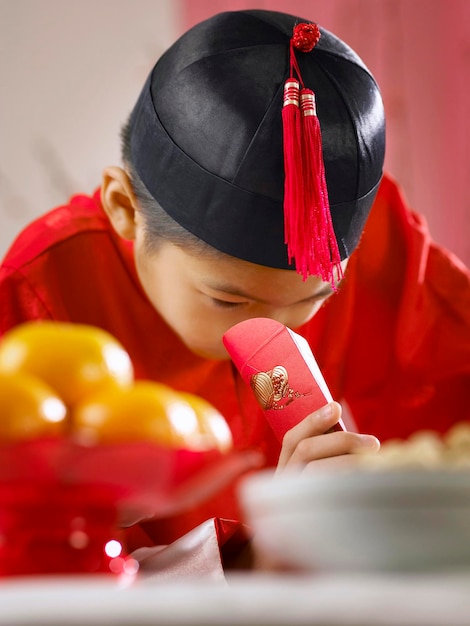 Close-up de um menino adolescente em roupas tradicionais olhando para um envelope