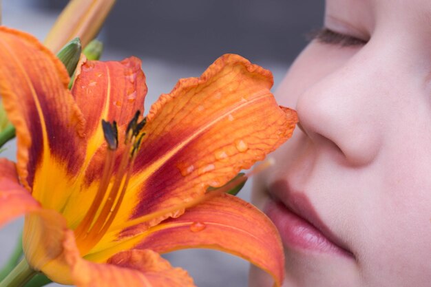 Foto close-up de um menino cheirando lírio de dia