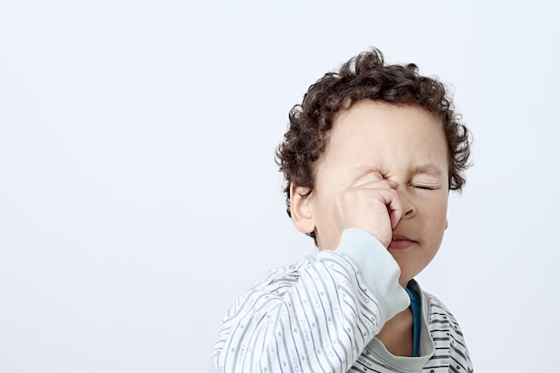 Close-up de um menino chorando contra um fundo cinzento