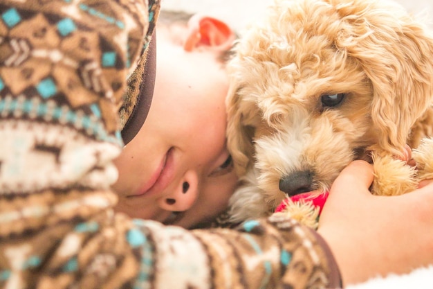 Close-up de um menino com um cachorrinho de labradoodle