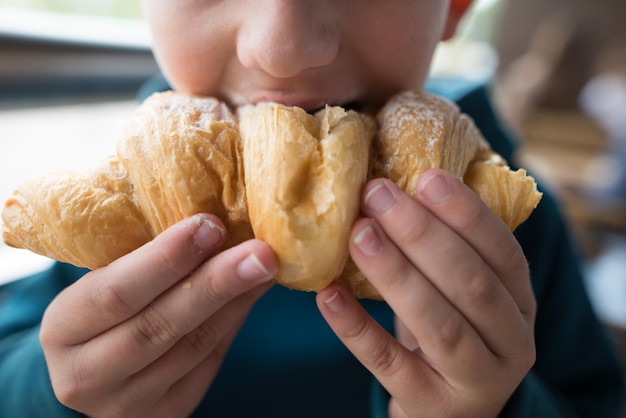 Close-up de um menino comendo um croissant Foto recortada