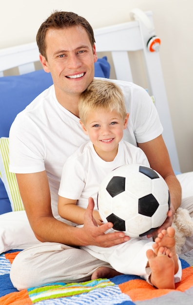 Close up de um menino e seu pai brincando com uma bola de futebol