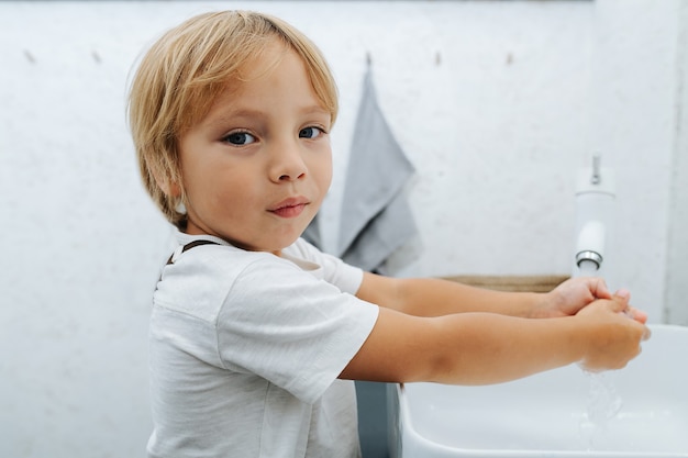 Foto close-up de um menino lavando as mãos na pia do banheiro