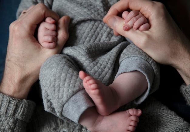 Close-up de um pai segurando as mãos de bebês recém-nascidos