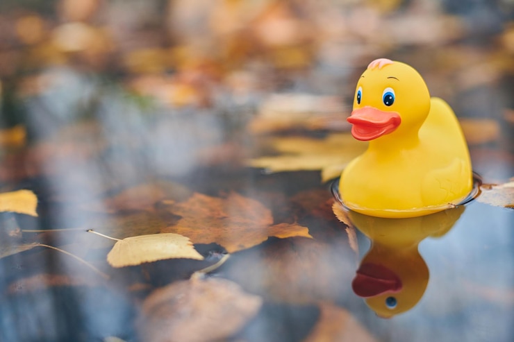 Foto close-up de um pato amarelo flutuando na água