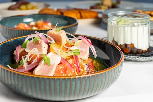 Close-up de um prato de atum fresco com legumes, juntamente com outros pratos de frutos do mar.