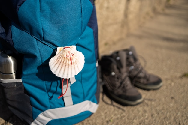 Foto close up de um símbolo de concha do caminho de santiago na mochila e botas de trekking