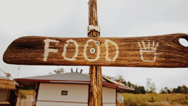 Close-up de um sinal de comida em um poste de madeira contra o céu