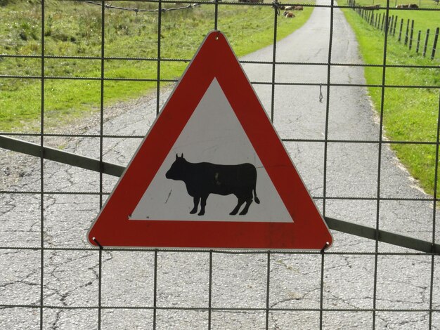 Foto close-up de um sinal em um portão metálico contra a estrada