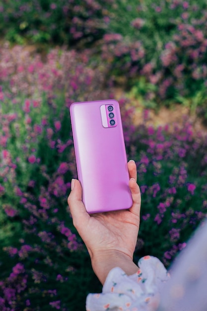 Foto close-up de um smartphone na mão de uma mulher em um fundo de flores rosa