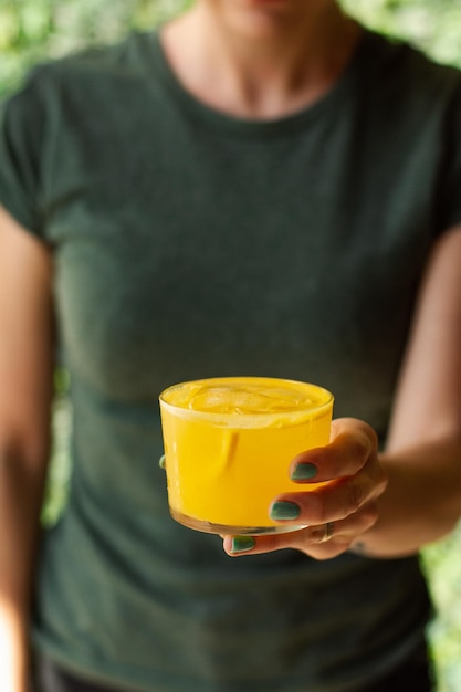 Close-up de um suco de laranja na mão da mulher