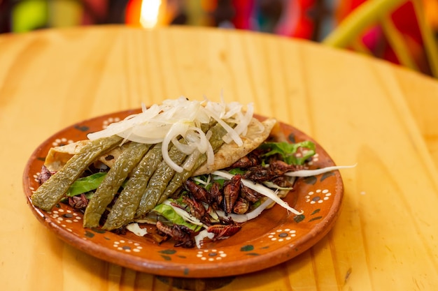 Close-up de um taco exótico mexicano feito com nopales de gafanhotos e cebola