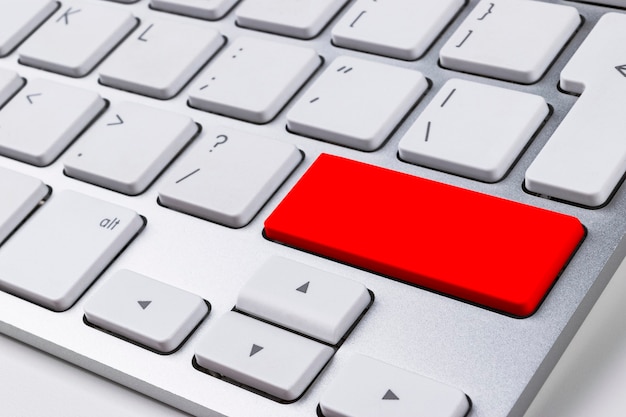 Close-up de um teclado de computador com um botão vermelho na mesa branca do escritório