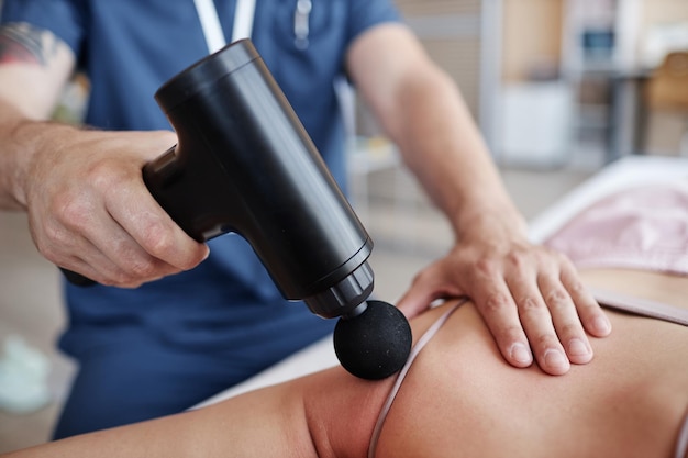 Close-up de um terapeuta massageando um paciente com equipamentos médicos em um hospital