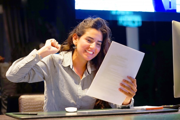 Close-up de um trabalhador de escritório. senhora feliz, aproveitando as boas notícias por escrito. uma garota eufórica fica feliz depois de ler boas notícias em uma carta escrita, aprovar um empréstimo e aumentar seu emprego.