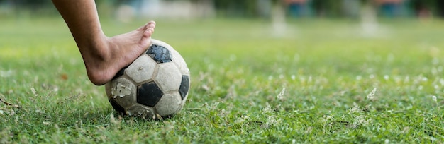 Foto close-up de um velho menino de futebol não usando sapatos pronto para chutar a bola no velho campo de futebol