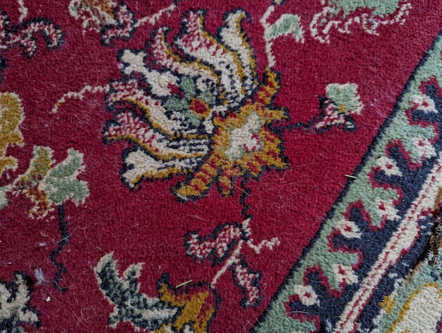 close-up de um velho tapete cor de vinho com um ornamento