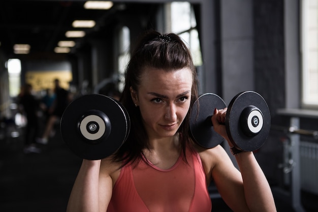 Close-up de uma atleta feminina focada se exercitando com halteres