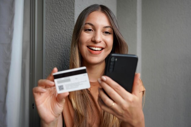Close-up de uma atraente garota hispânica fazendo uma compra no smartphone com cartão de crédito