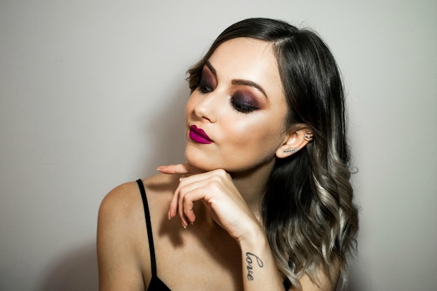 Foto close-up de uma bela jovem usando maquiagem contra a parede