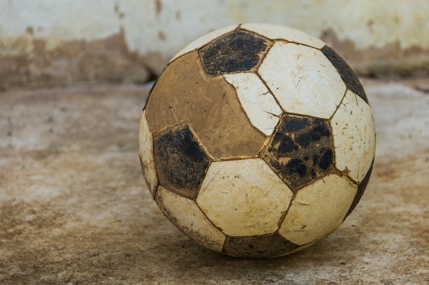 Foto close-up de uma bola de futebol abandonada na calçada contra a parede