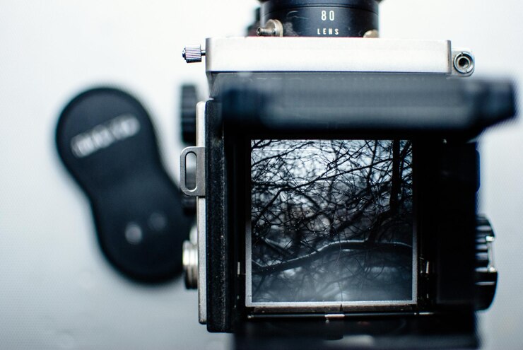 Foto close-up de uma câmera vintage fotografando árvores nuas durante o inverno