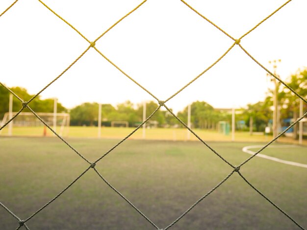 Close-up de uma cerca de liga de cadeia em um campo de futebol contra o céu