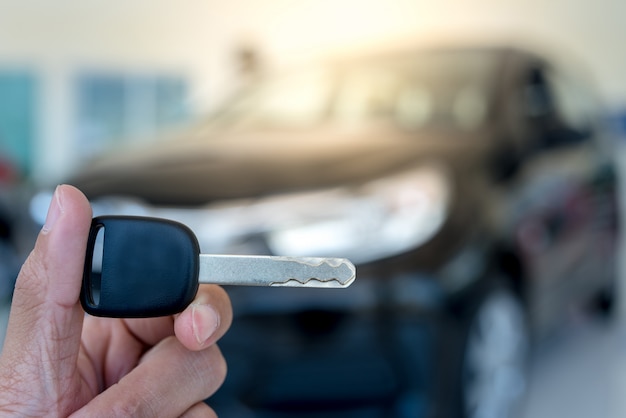 Close-up de uma chave de carro - um jovem segurando uma nova chave de carro no showroom de carros, nova chave