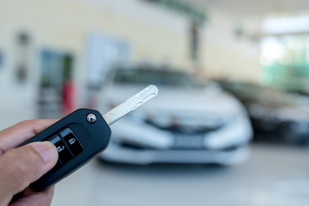 Close-up de uma chave de carro - um jovem segurando uma nova chave de carro no showroom de carros, nova chave