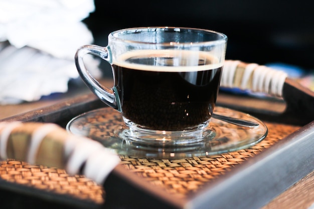 Close-up de uma chávena de café preto servida em uma chácara de vidro em uma bandeja