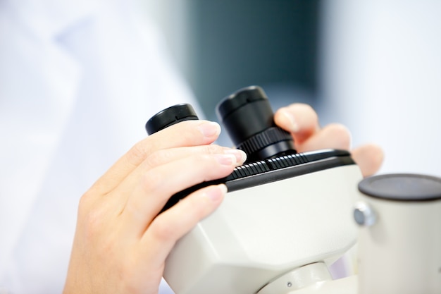 Close-up de uma cientista feminina olhando através de um microscópio