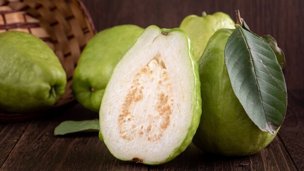 Close-up de uma deliciosa e linda goiaba com folhas verdes frescas isoladas em uma mesa de madeira