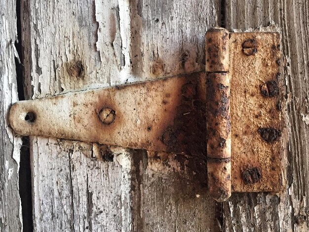 Foto close-up de uma dobradiça enferrujada em uma porta desgastada