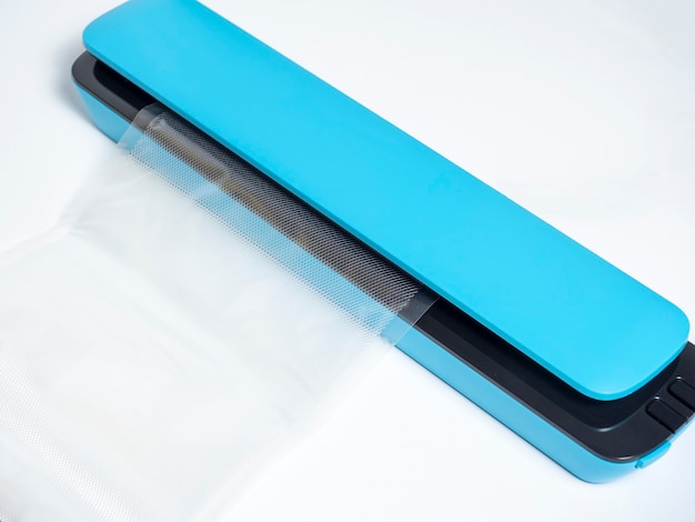 Close-up de uma embaladora a vácuo azul, isolada em um fundo azul brilhante. o pacote é inserido na máquina. Ferramentas para preservar a frescura dos produtos. Camada plana, vista superior.