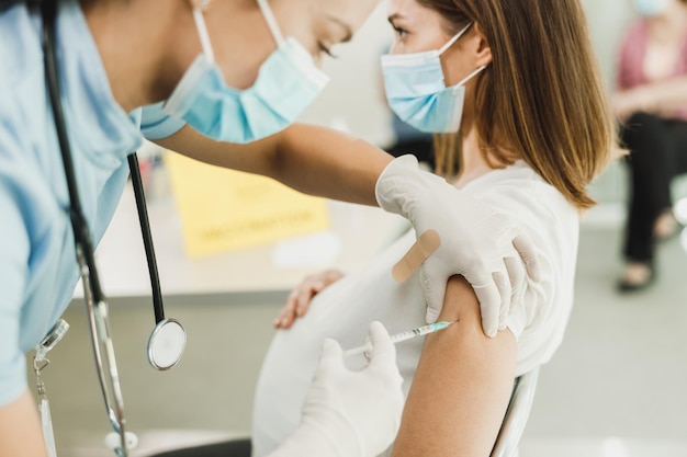 Close-up de uma enfermeira dando uma vacina a uma mulher grávida devido à pandemia de coronavírus.