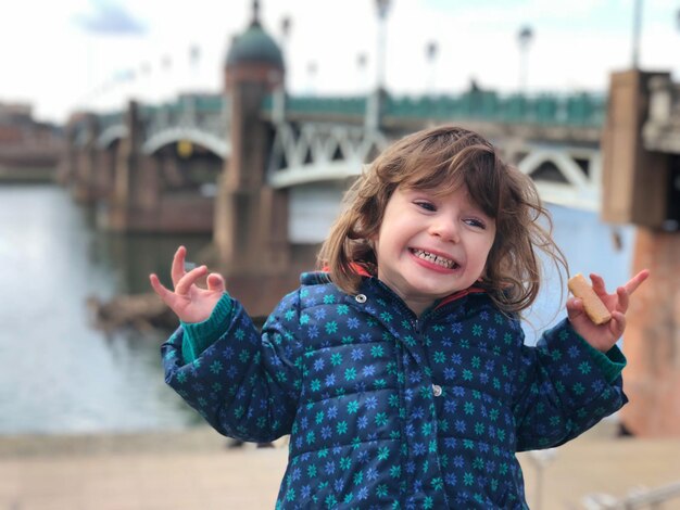 Foto close-up de uma garota feliz de pé contra o rio na cidade