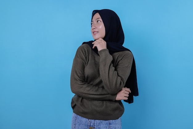 Close-up de uma garota feliz usando um hijab em um pano casual e sorrindo na parede azul